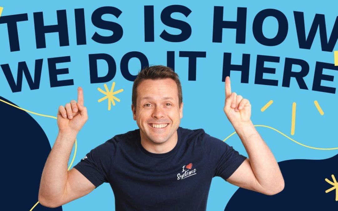 David Jenyns smiling and pointing upward wearing an 'I Love Systems' t-shirt with text 'This Is How We Do It Here'