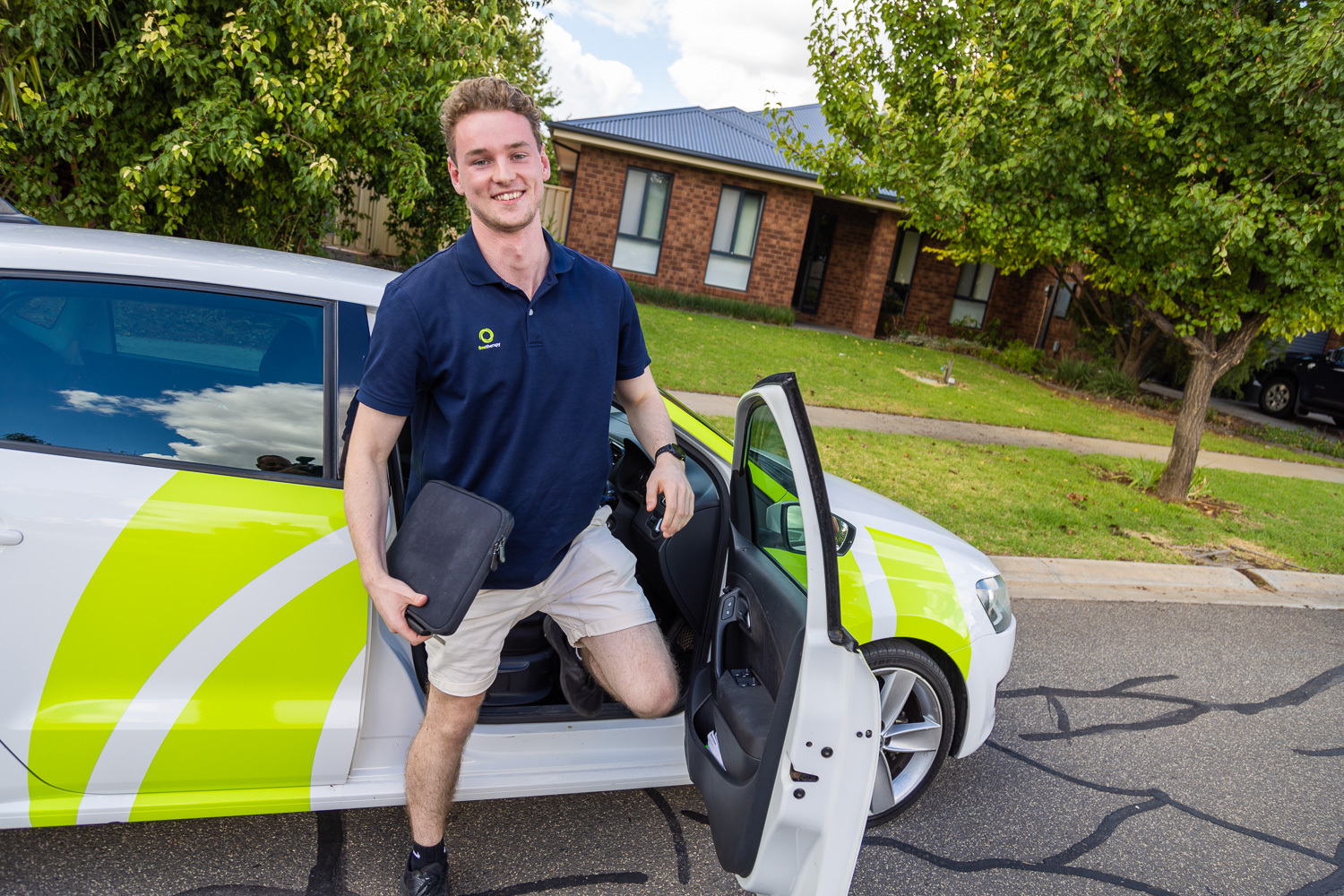 Kaleb Grant standing beside a company car